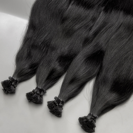 A set of black K-tip hair extensions laid out on a white surface.