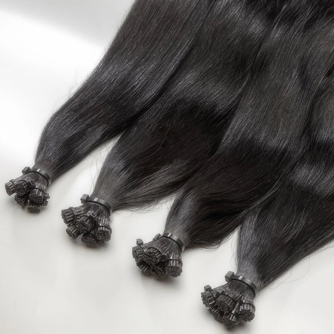 A close-up of black I-tip hair extensions with a decorative element on the tip.