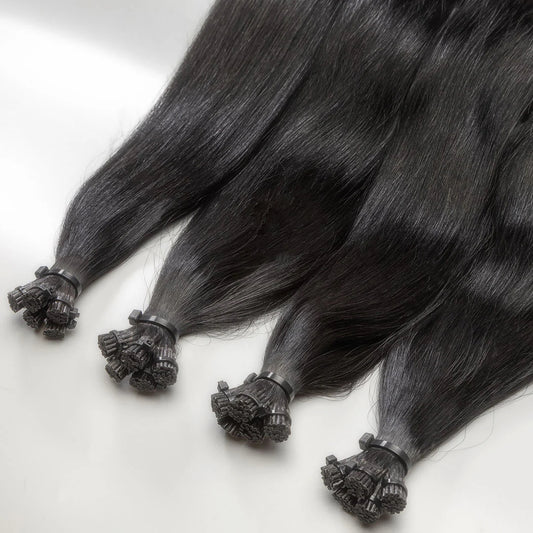 A close-up of black I-tip hair extensions with a decorative element on the tip.
