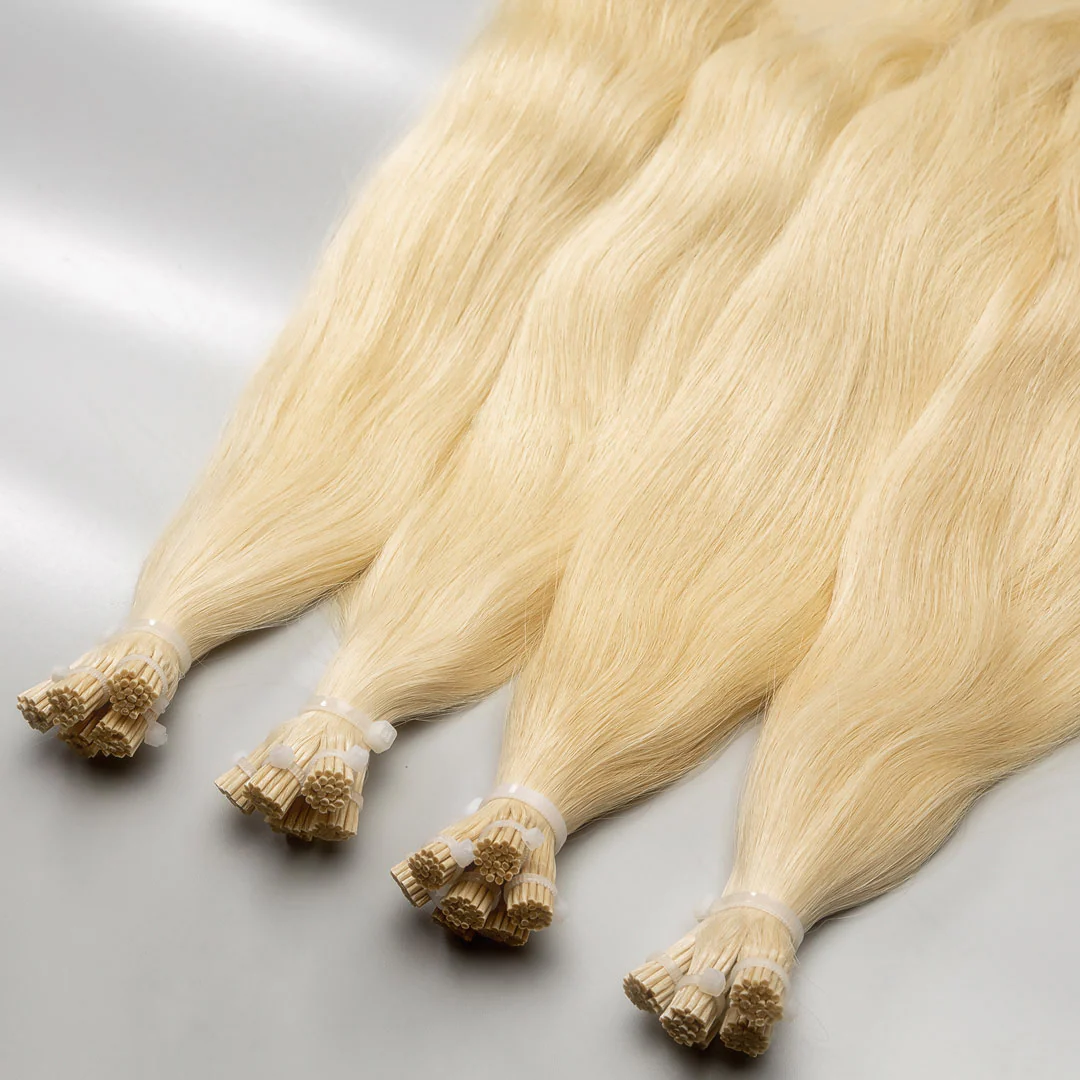 A collection of light blonde I-tip hair extensions laid out on a surface.