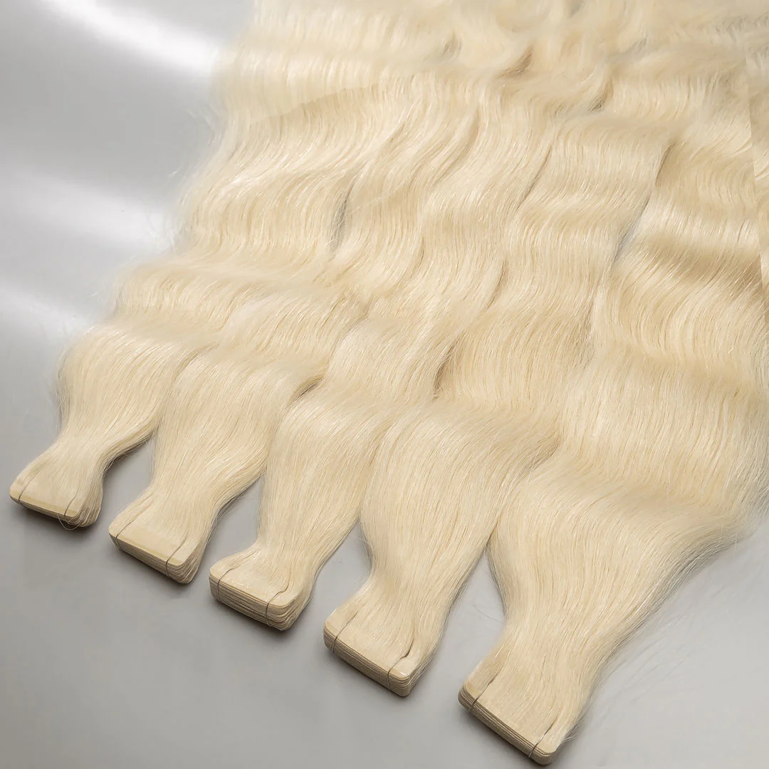 A collection of light blonde tape-in hair extensions laid out on a surface.