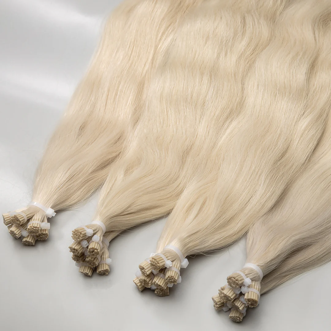 A collection of platinum blonde I-tip hair extensions tied in bunches with small beads, displayed on a white surface.