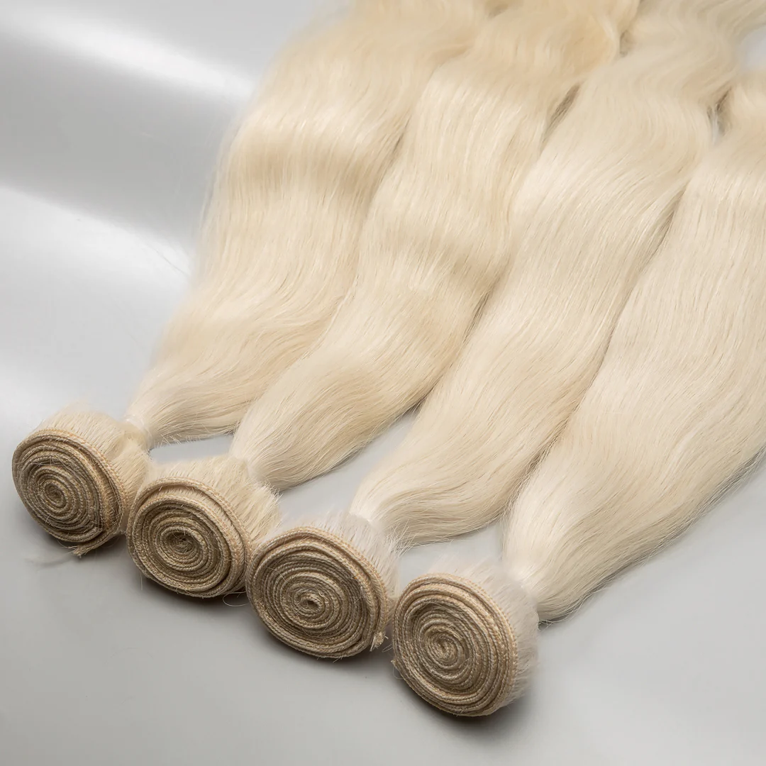 A collection of platinum blonde weft hair extensions tied in bunches, displayed on a grey background.