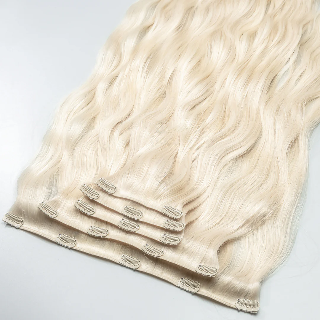 A clip-in hair extension piece with platinum blonde color, consisting of real human hair attached to small clips.