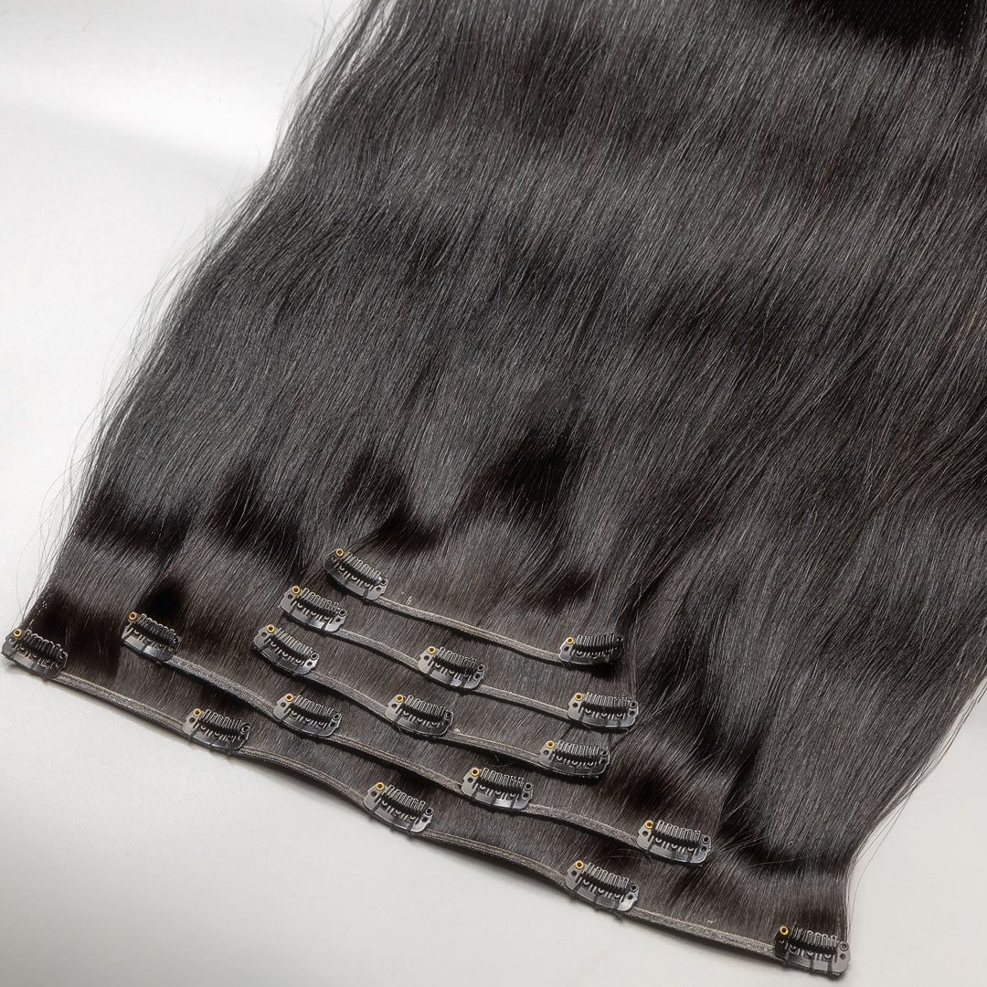 A section of black clip-in hair extensions with visible clips and strands of hair.