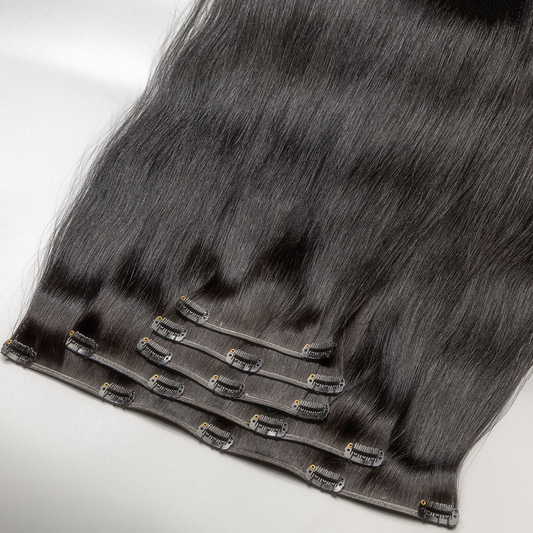 A section of black clip-in hair extensions with visible clips and strands of hair.
