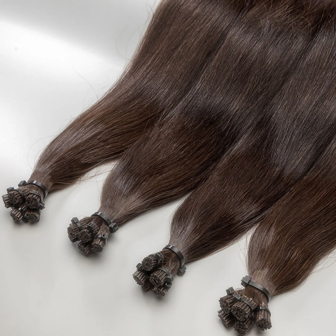A close-up image of I-tip hair extensions with a brown color, displayed in a way that shows the individual strands and the small beads used for attachment.
