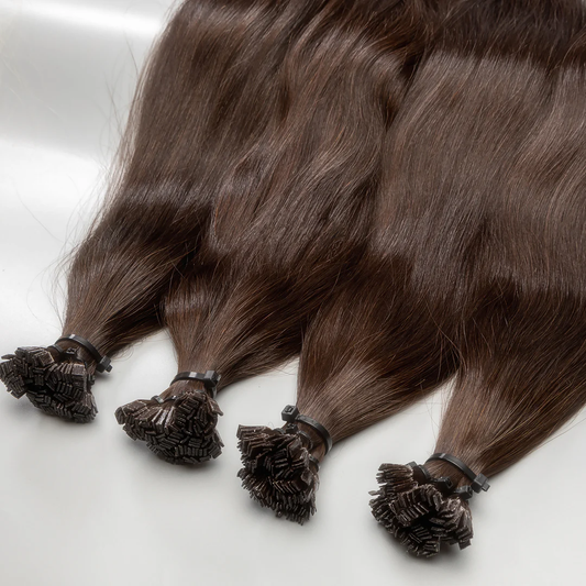 A collection of medium brown K-tip hair extensions displayed on a white surface.