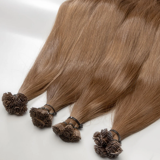 A set of lightest brown premium human hair K-tip extensions displayed on a white surface.