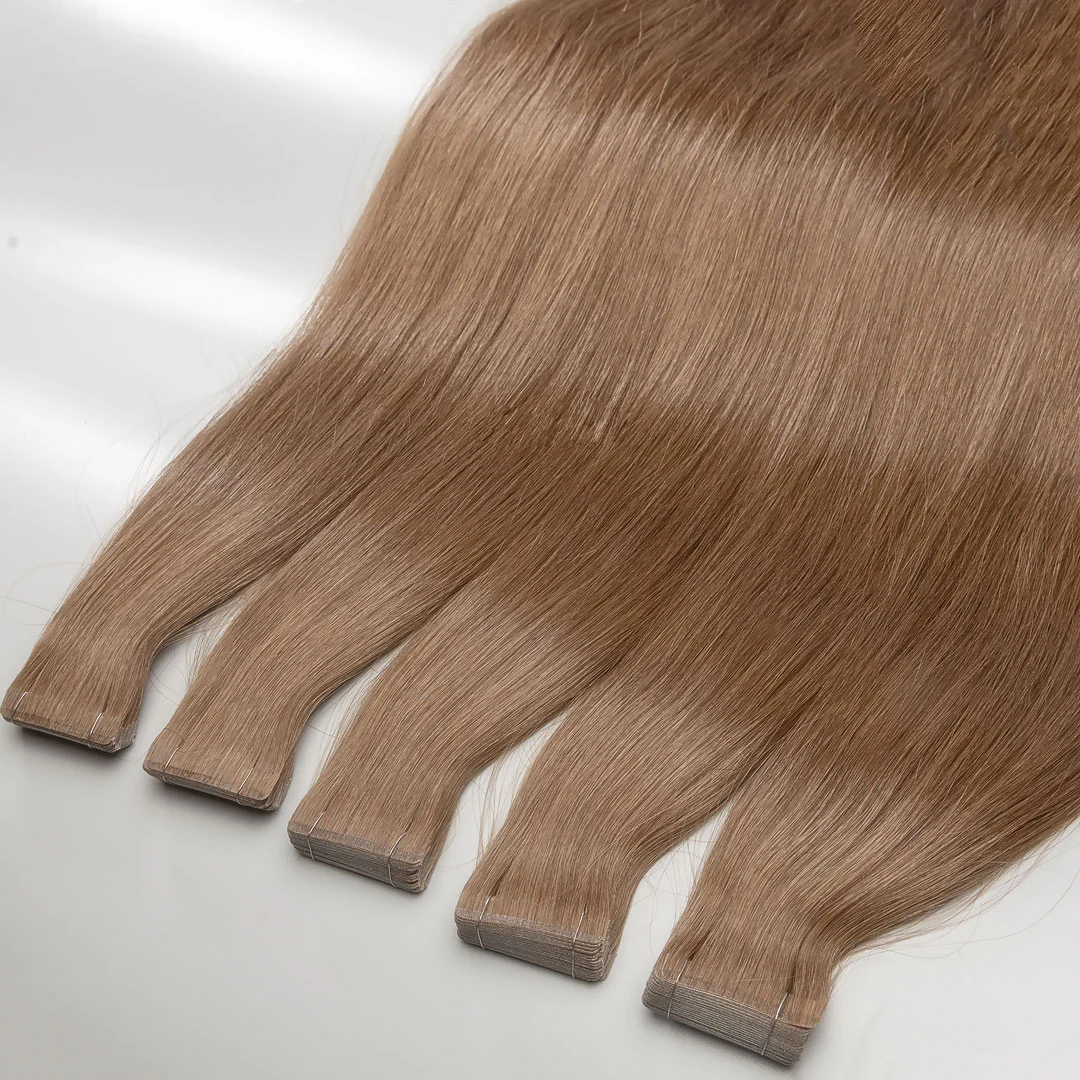 A set of light brown tape-in hair extensions laid out on a surface.