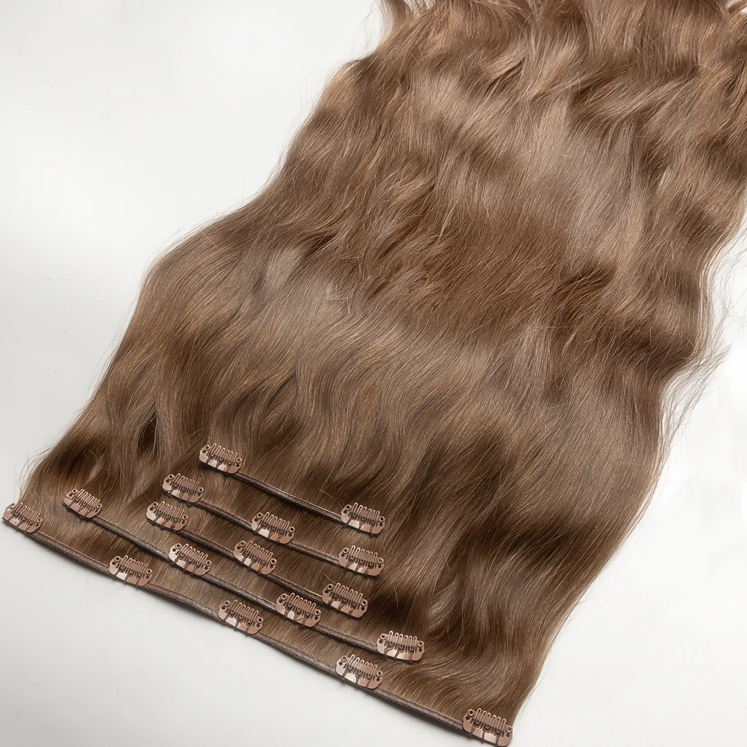 A section of clip-in hair extension with ash light blonde color, featuring real human hair attached to small metal clips.