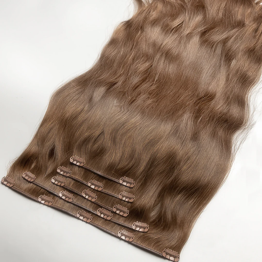 A section of clip-in hair extension with ash light blonde color, featuring real human hair attached to small metal clips.