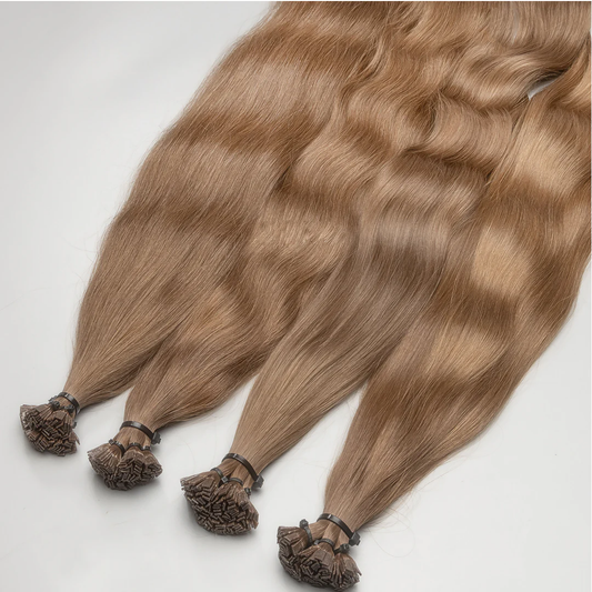 A bundle of golden dark blonde K-tip hair extensions with keratin bonds.
