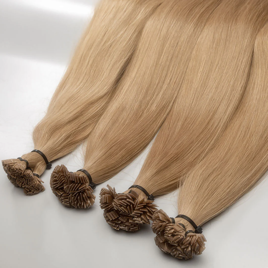 A set of K-tip hair extensions with a light blonde color, displayed in a fan-like arrangement, showing the natural texture and length of the hair.