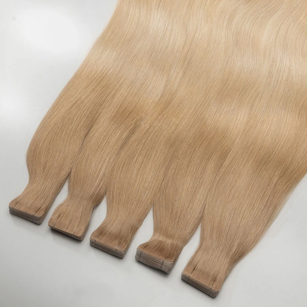 A set of tape-in hair extensions laid out in a fan-like arrangement, displaying golden blonde color.